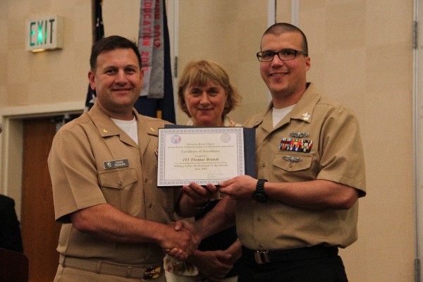Lt. Cmdr. Dave Pereira, USN, (l) chapter vice-president of military affairs, presents the June Military Cyber Professional of the Month to Petty Officer 1st Class Thomas Brandt, USN, Naval Computer Telecommunications Area Master Station, Atlantic. Teresa Duvall, chapter president, stands witness.